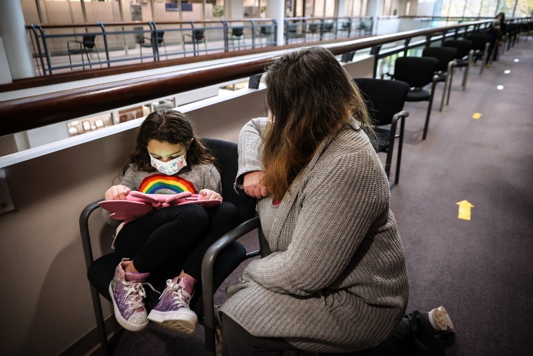 A girl watches her iPad while sitting in the post-injection waiting area at the Fairfax County Government Center on Nov. 4, 2021 in Annandale, Va.