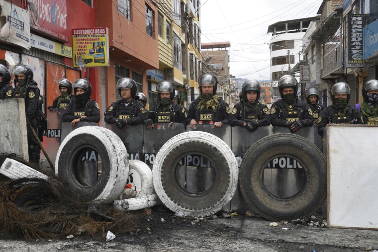 Police stand guard behind a barricade in Andahuaylas, Peru