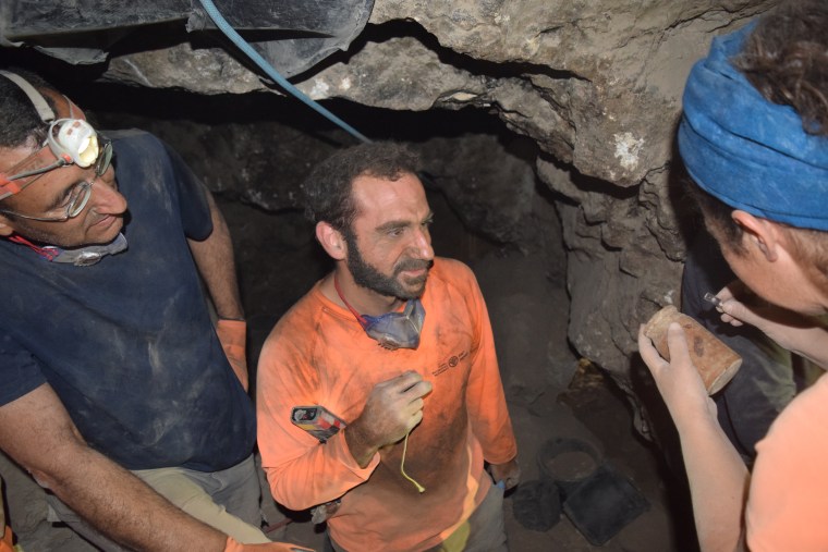 Excavation teams examine a wooden box containing the coins upon its discovery. 