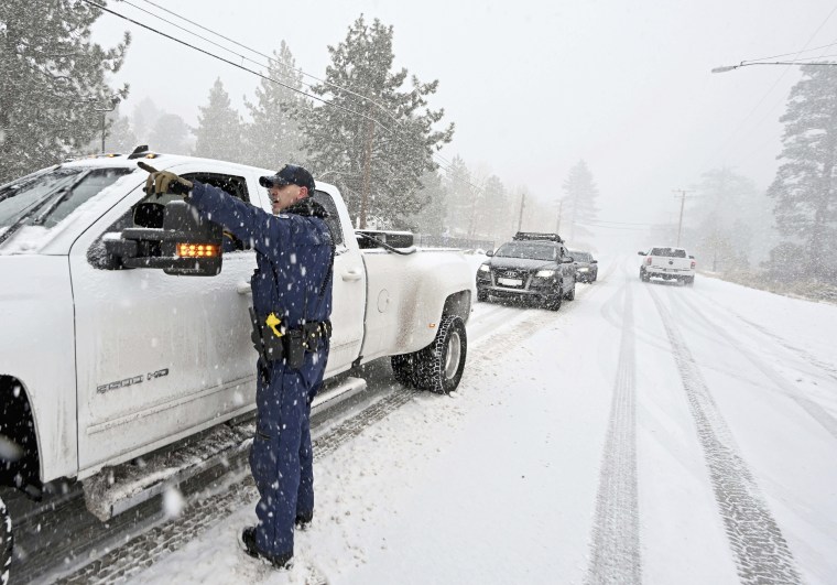 California Highway Patrol officer Mike Eshleman instructs a driver he may continue on Highway 2 in his 4-wheel drive vehicle as heavy snow falls near Wrightwood, Calif., on Dec. 12, 2022. 