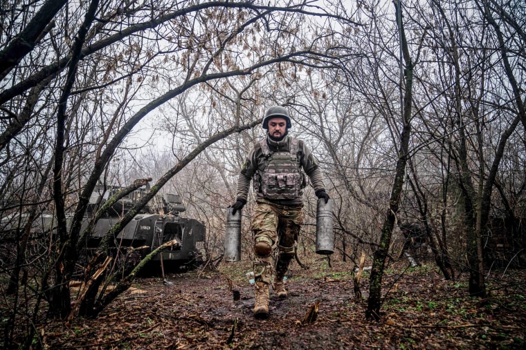 ウクライナ戦争 A Ukrainian soldier carries empty artillery cartridge cases at a position along the front line in the vicinity of Bakhmut, Donetsk region, on Dec. 10, 2022.