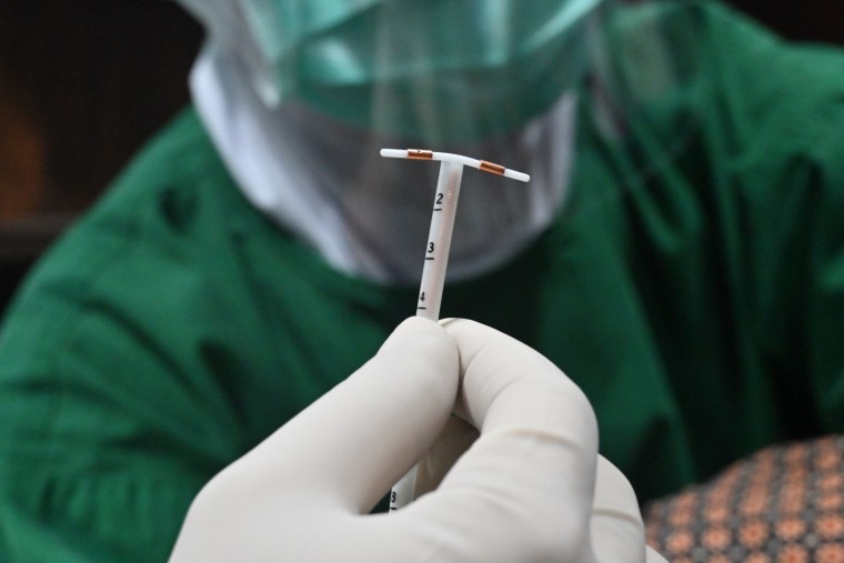 A doctor holds an IUD birth control device. 