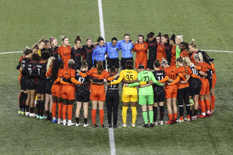 Portland Thorns and Houston Dash players, along with referees, gather at midfield, in demonstration of solidarity with two former NWSL players who came forward with allegations of sexual harassment and misconduct against a prominent coach