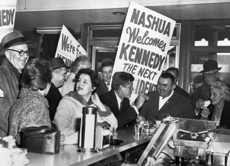 John F. Kennedy sits at a counter with some of his supporters while campaigning for president in a Nashua, New Hampshire