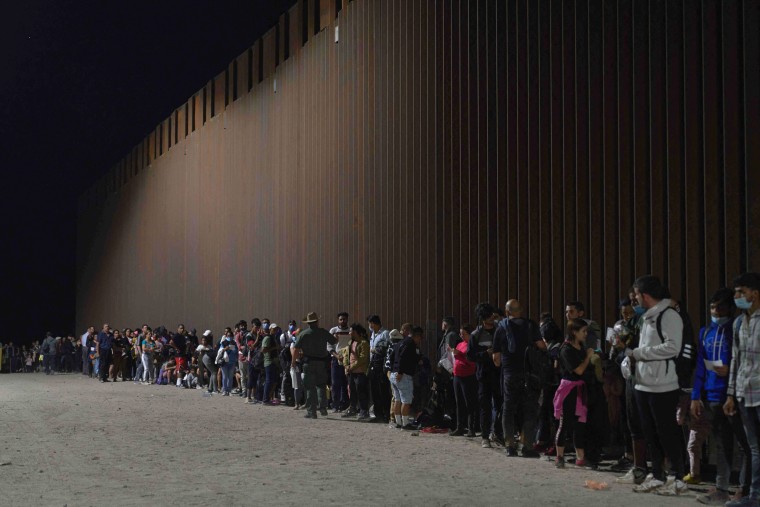 Migrants wait to be processed by the U.S. Border Patrol after illegally crossing the U.S.-Mexico border in Yuma, Ariz., early on July 11, 2022.