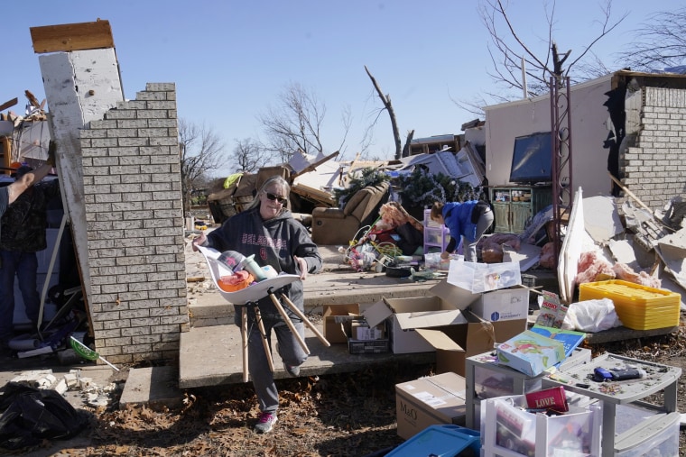 Belinda Penner carries belongings from her cousin's home after a tornado tore through the area in Wayne, Okla.