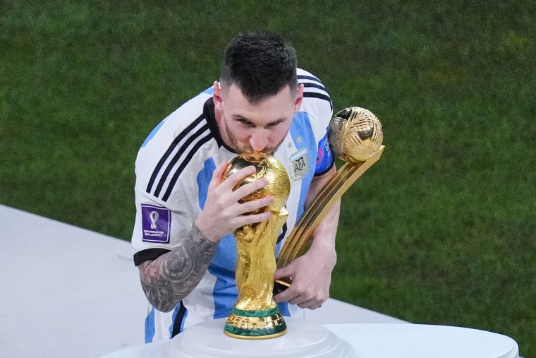 Argentina's Lionel Messi, holding the Golden Ball award for best player of the tournament, kisses the World Cup in Lusail, Qatar, on Dec. 18, 2022.