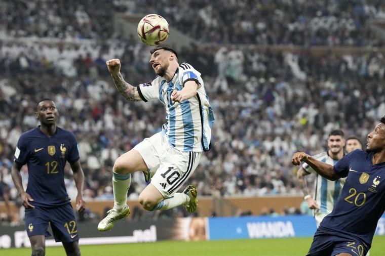 Argentina's Lionel Messi heads the ball next to France's Kingsley Coman, right, during the World Cup final in Lusail, Qatar, on Dec. 18, 2022.