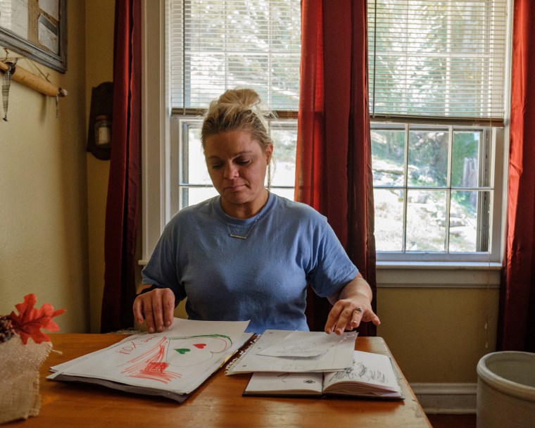 Jackie Snodgrass sitting in her dining room looking at notes and drawings made by her daughers