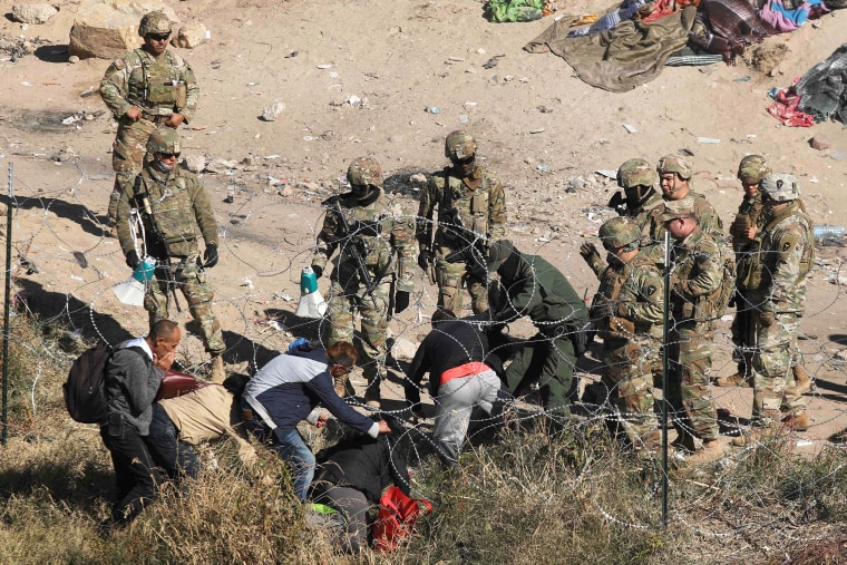 Migrants cross the razor fence placed by elements of the Texas National Guard on the banks of the Rio Grande, in El Paso, Texas, US. border with Ciudad Juarez, Chihuahua state, Mexico, on December 20, 2022. - Title 42, a President Donald Trump pandemic-era law that authorize United States border officials to expel migrants is supposed to end on December 21.