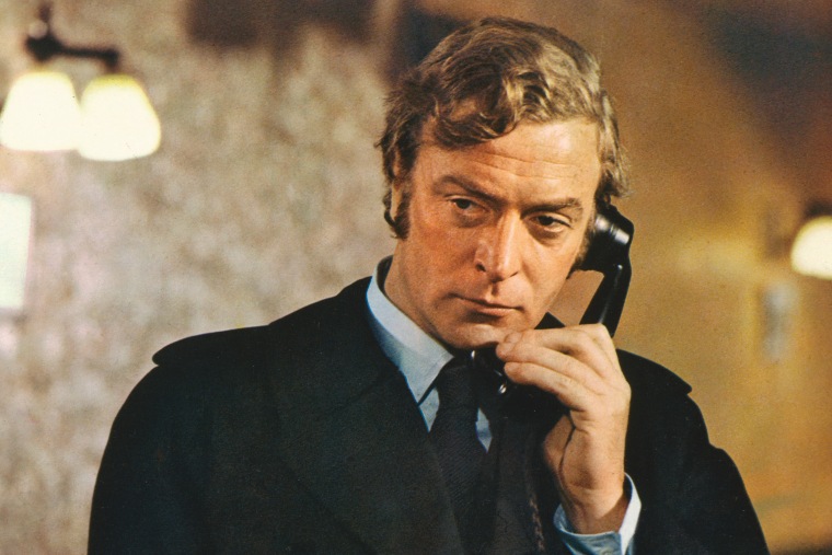 Michael Caine, British actor, wearing a black raincoat and holding a black telephone receiver in a publicity still issued for the film, 'Get Carter', United Kingdom, 1971. The crime thriller, directed by Mike Hodges, starred Caine as 'Jack Carter'. (Photo by Silver Screen Collection/Getty Images)