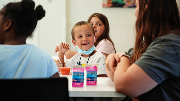 Six-year-old Timmy Schoolcraft smiles at library volunteer Reta Borton, 15, during the free summer lunch and snack program at the South High Branch of the Columbus Metropolitan Library in Columbus, Ohio, on June 10, 2022.