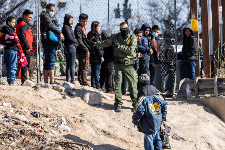 A U.S. Border Patrol agent instructs immigrants who had crossed the Rio Grande into El Paso, Texas, on Dec. 19, 2022.