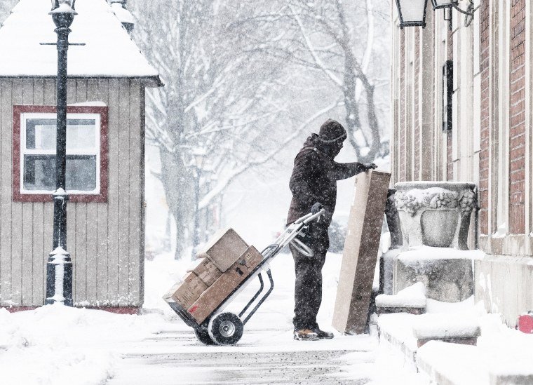 A UPS worker delivers packages during a snow storm