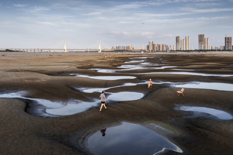 People walk on the exposed banks due to low water levels caused by drought, along the Yangtze River, in Wuhan, China