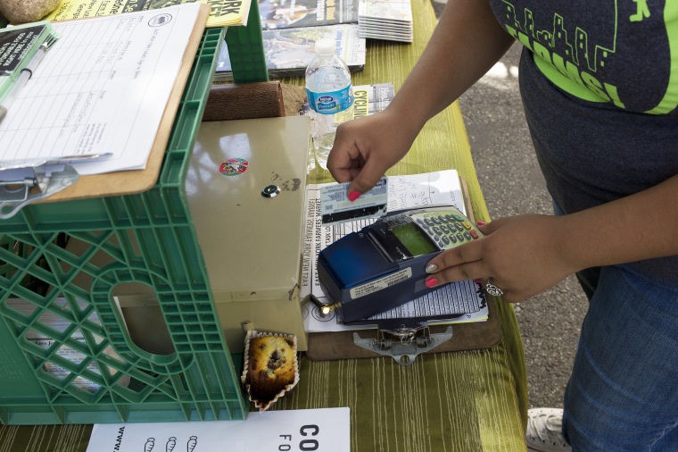 A person swipes an EBT card at a farmers market in New York.
