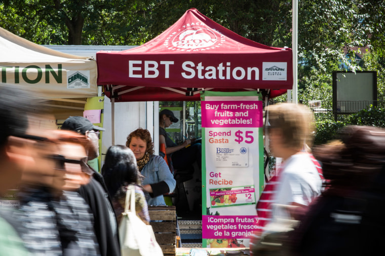 People walk past an EBT station in the GrowNYC Greenmarket