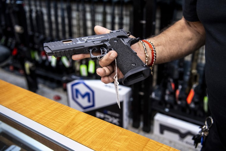 A salesperson shows a hand gun available for purchase at a firearms store