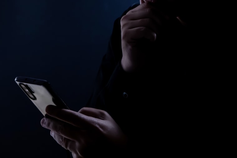 Silhouette of a man using a mobile phone in the dark