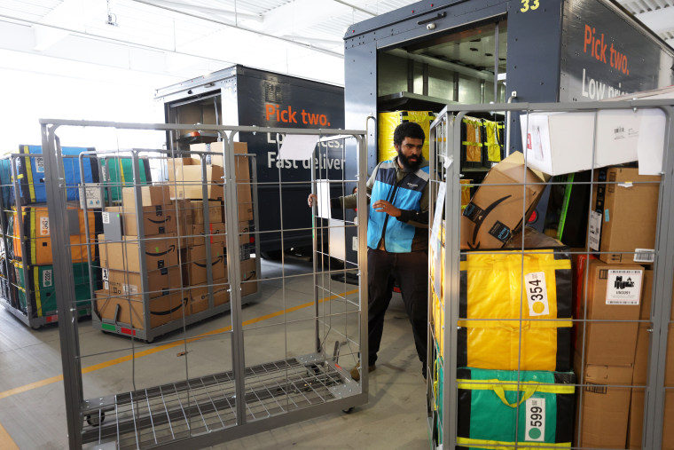 An Amazon driver loads packages into a delivery van