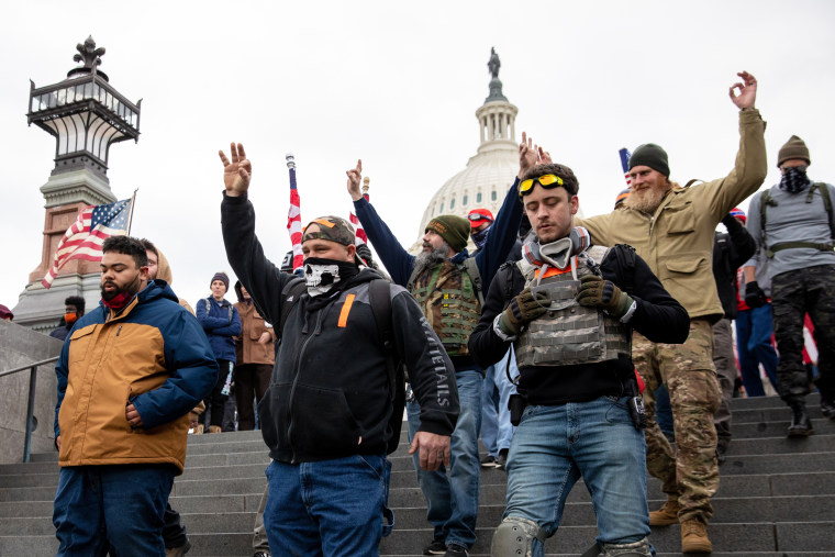 Members of the Proud Boys make a hand gesture while walking near the Capitol