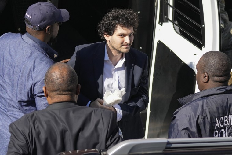 Sam Bankman-Fried, center, is escorted arrives at the Magistrate Court building for a hearing