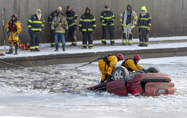 Fire department rescue workers work to recover a minivan that went into Brush Creek in Kansas City, Mo., on Dec. 22, 2022.