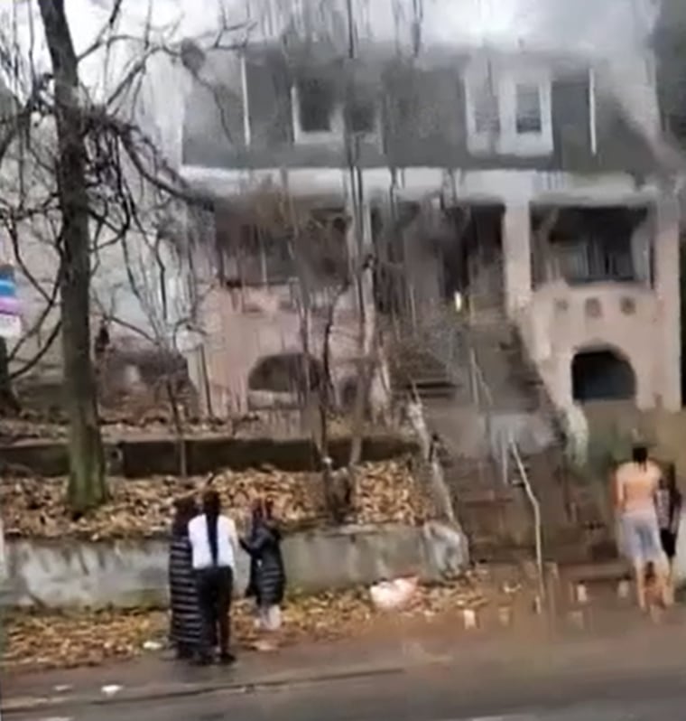 People stand outside a house fire Friday morning in New York City's Staten Island