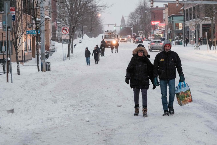 People walk along a snow-covered street in Buffalo, N.Y.