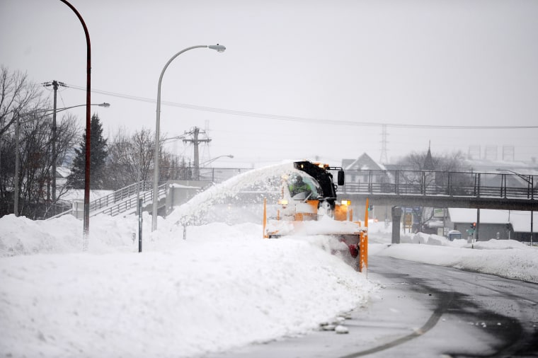 A snow blower removes heavy snow from a street in Hamburg, N.Y.