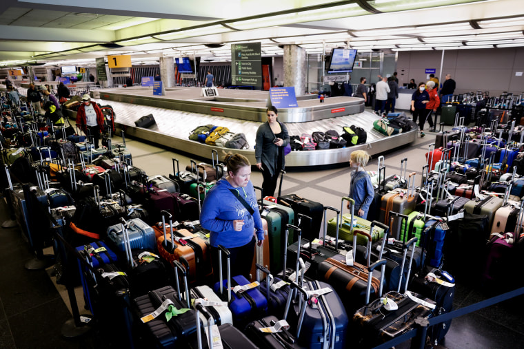 Travelers search for their suitcases in a baggage holding area at Denver International Airport on Dec. 28, 2022.