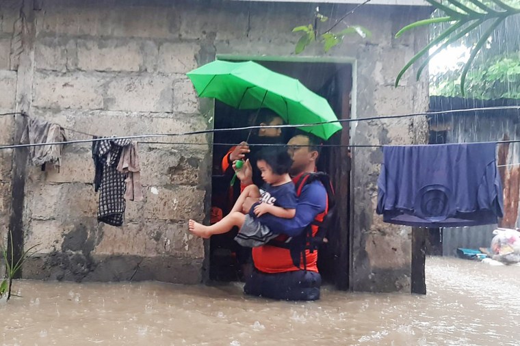 Rescuers evacuate a child from a flooded area in Ozamiz City, Philippines on Dec. 25, 2022. 