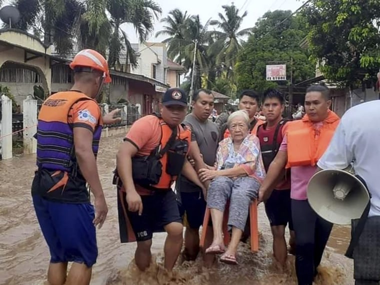An elderly woman is carried by coast guard personnel wading through floodwaters in Plaridel, southern Philippines, on Dec. 26, 2022. 