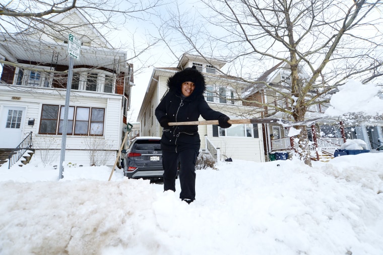 A woman clears snow from her driveway in Buffalo, N.Y.