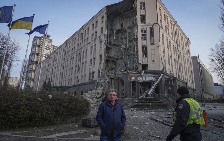 People stand in front of damaged hotel at the scene of Russian shelling in Kyiv