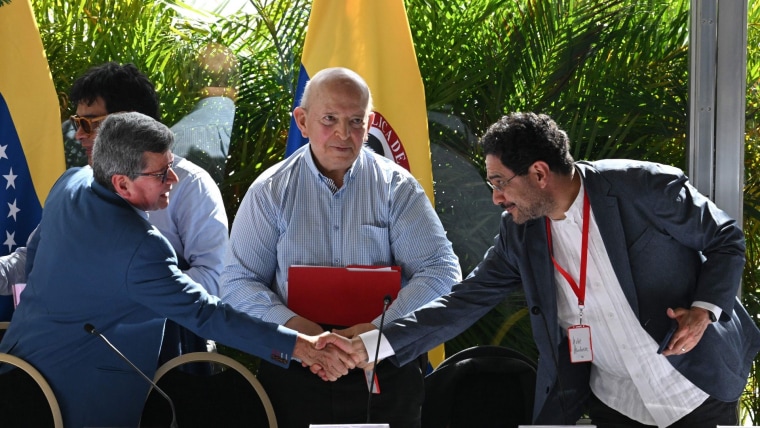 Pablo Beltrán del ELN (izq.) le da la mano a Iván Cepeda, negociador del Gobierno colombiano, frente a Otty Patiño (centro), delegado del Gobierno, al cierre de la primera ronda de negociaciones entre autoridades y el Ejército de Liberación Nacional el 12 de diciembre de 2022