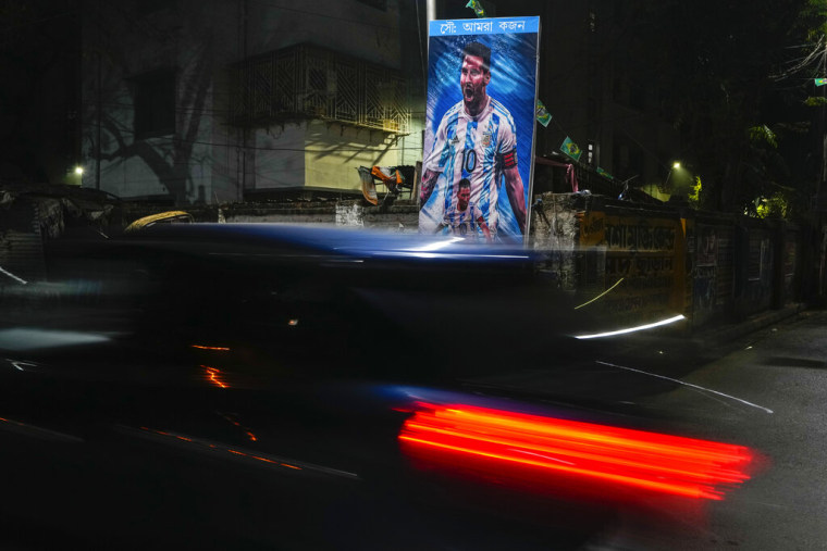 Un auto pasa junto a un cartel del futbolista argentino Leonel Messi, colocado por hinchas indios durante la semifinal entre Argentina y Croacia.