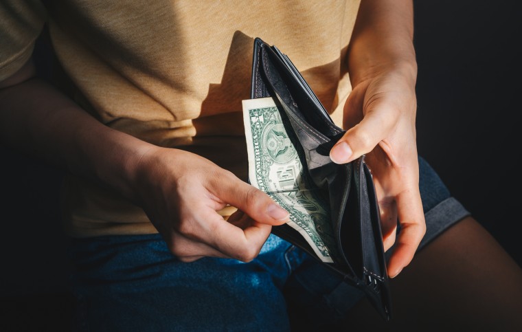 Imagen de archivo de una persona sacando un dólar de su billetera.