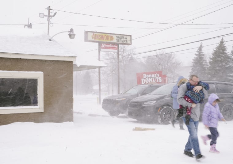 Una familia cruza un estacionamiento en medio de los estragos de la tormenta invernal en Flint, Michigan, el 23 de diciembre de 2022.