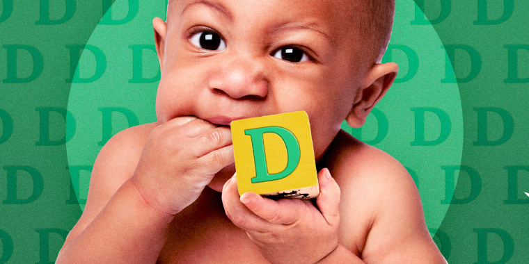 baby teething on their fingers and holding a alphabet block with the letter D