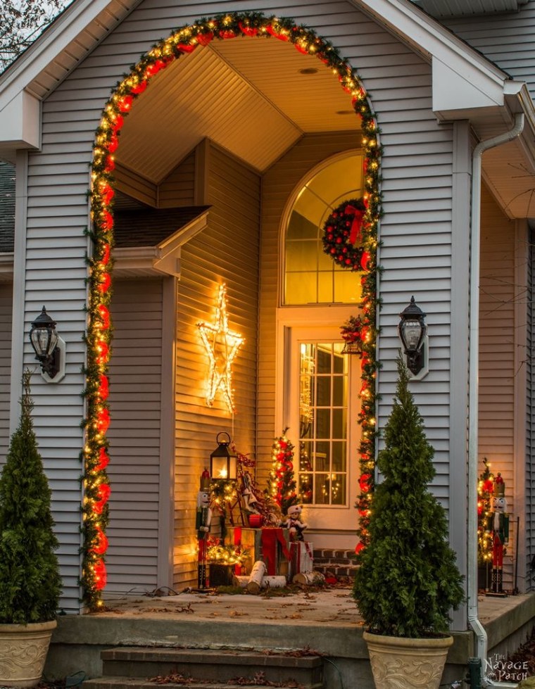 green garland with red ribbon and twinkle lights around an archway