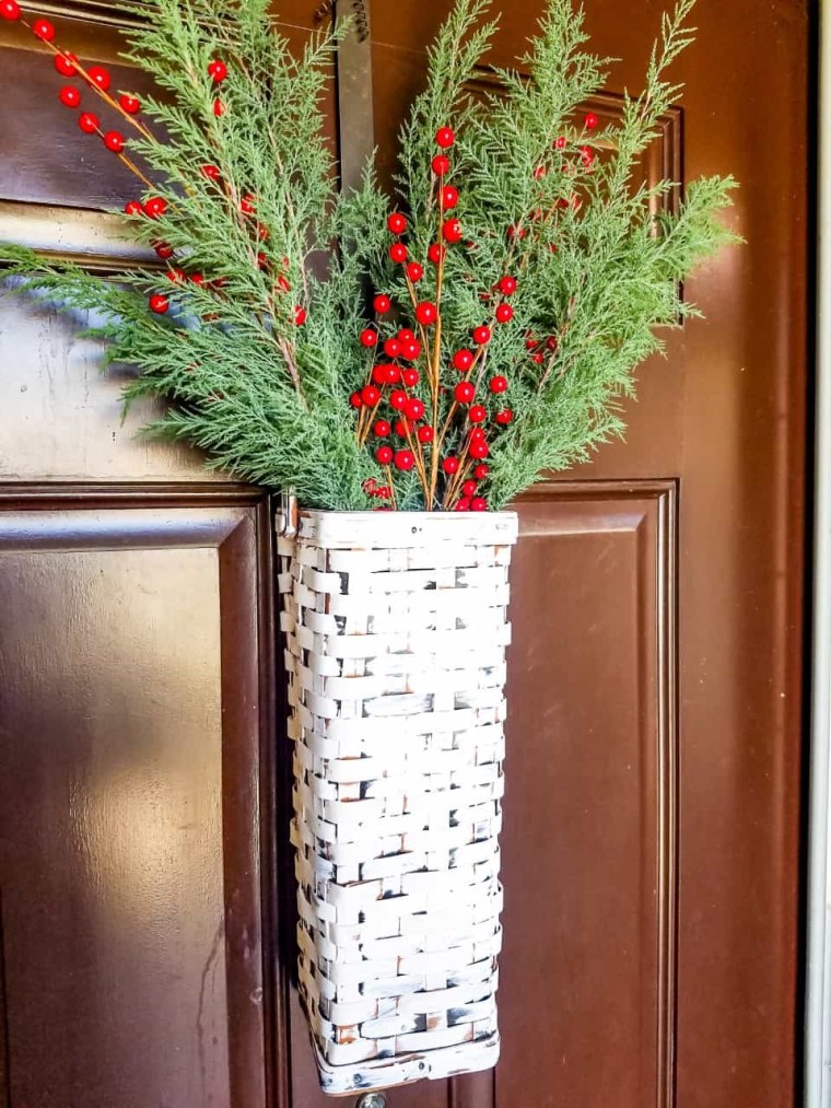 white door basket with greens and holly inside