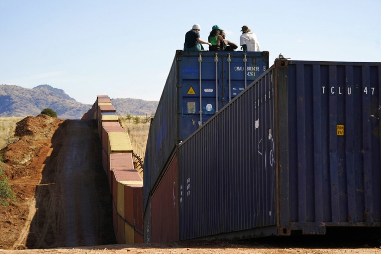 Activistas se sientan en contenedores de envío recién instalados a lo largo de la frontera creando un muro entre Estados Unidos y México en el Valle de San Rafael, Arizona, el jueves 8 de diciembre de 2022.
