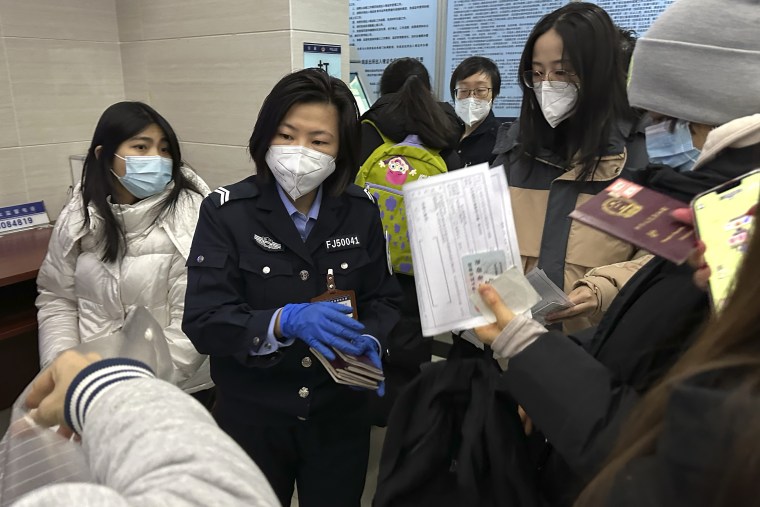 Un oficial recoge los pasaportes de los residentes para la renovación y re-aplicaciones en una estación de policía de la comunidad en Beijing, miércoles, 28 de diciembre 2022.