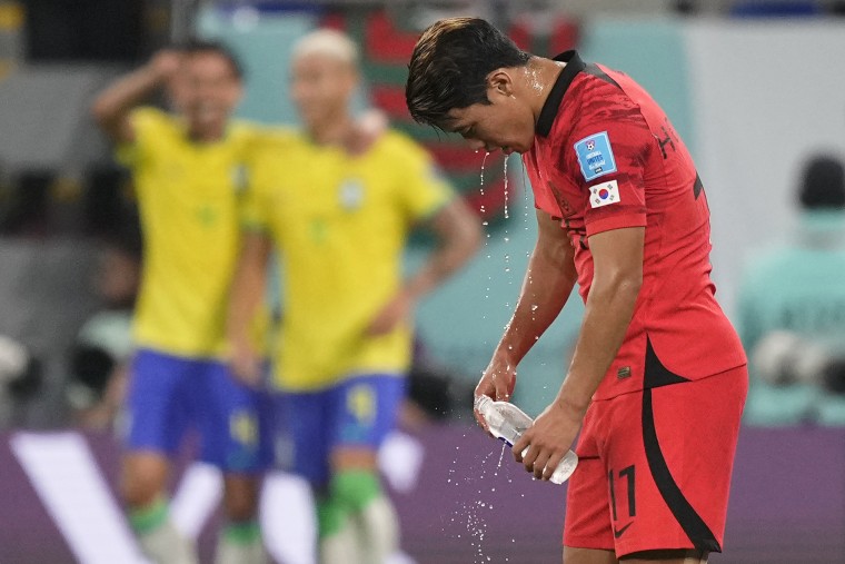 Hwang Hee-chan de Corea del Sur se casa con la cara mientras Richarlison de Brasil, segundo a la izquierda, celebra después de marcar el tercer gol de su equipo durante el partido.