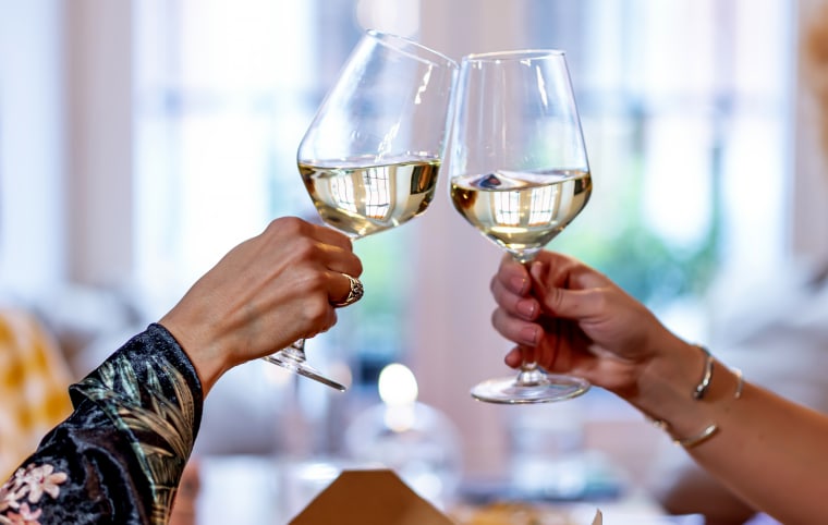Woman's hands hold glasses while toasting.