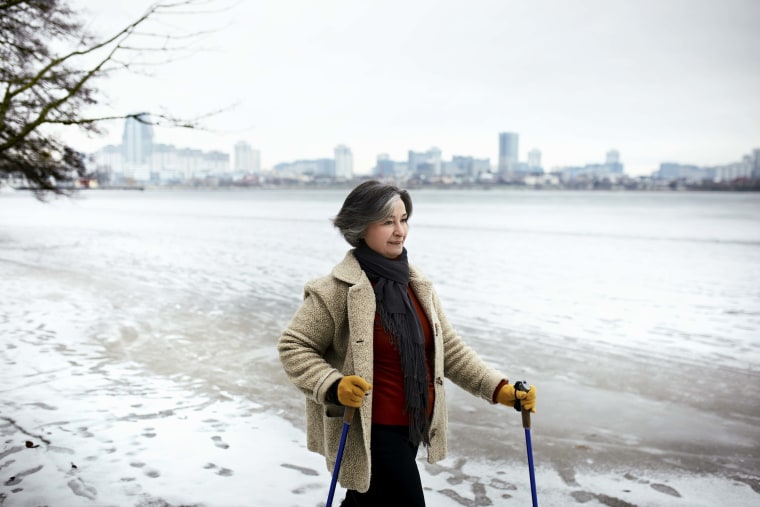 Active senior woman doing nordic walking at the waterfront in winter