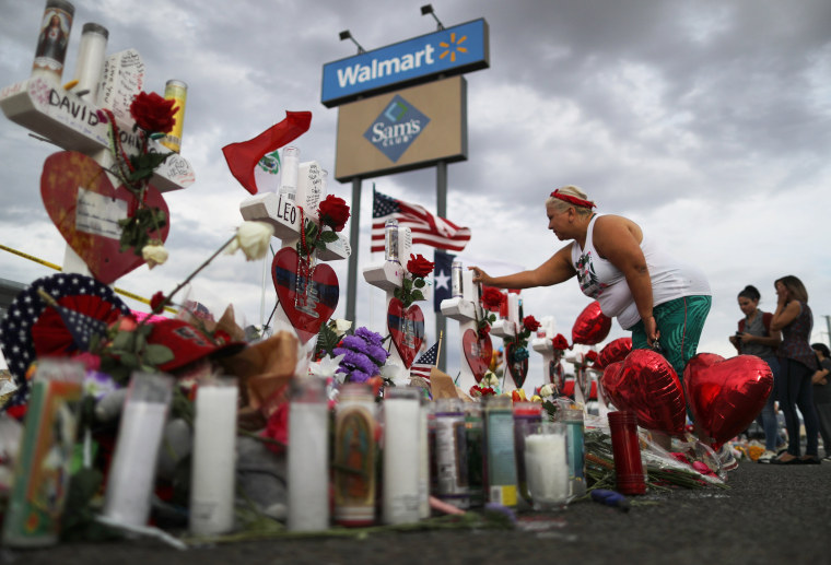 A woman touches a cross at a makeshift memorial for victims outside Walmart, near the scene of a mass shooting which left at least 22 people dead, on August 6, 2019 in El Paso, Texas. A 21-year-old white male suspect remains in custody in El Paso, which sits along the U.S.-Mexico border. President Donald Trump plans to visit the city August 7.