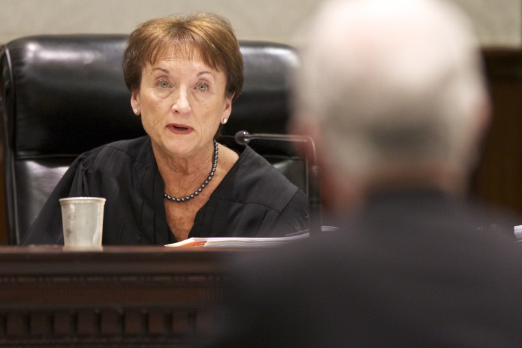 Photo of Supreme Court Justice Kaye Hearn speaking to a man in the foreground.