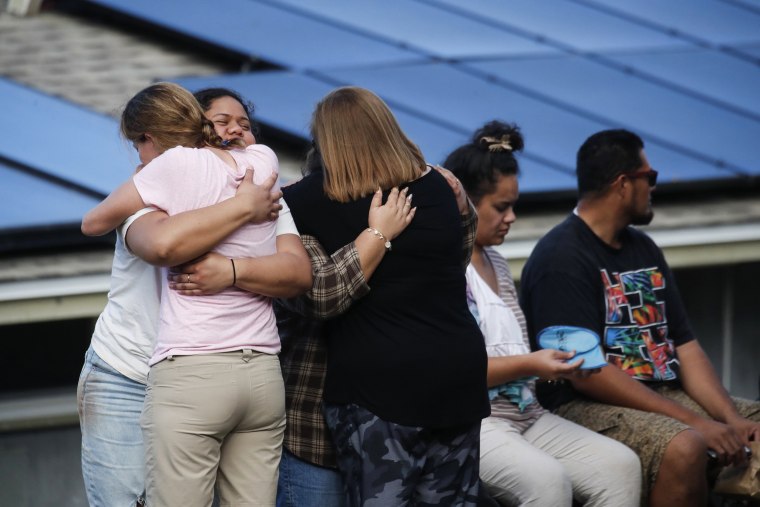 People embrace on a street in Kailua where a man died and a few others were seriously injured while building a retaining wall in Honolulu on Dec. 30, 2022.